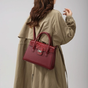 Détail du sac à main bordeaux en cuir façon crocodile porté avec un trench-coat