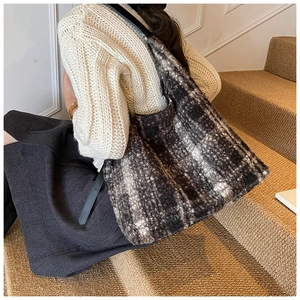 Detail of checkered tote bag made of thick tweed material with a black leather shoulder strap
