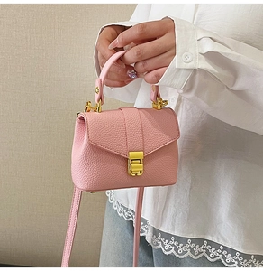 Detail of pink lychee leather mini handbag with gold clasp and top handle for women