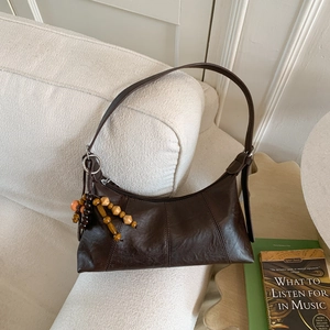 Sac hobo vintage marron foncé en cuir ciré avec pendentif en perles de bois sur canapé