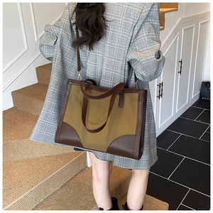 Close-up of contrast stitching tote bag with vintage canvas and leather panels on a model