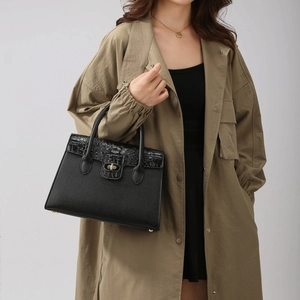 Détails du sac noir montrant le contraste entre cuir grainé et motif crocodile