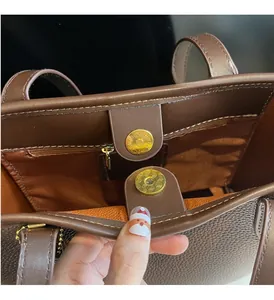 Detail of deep brown pebble leather tote showing golden magnetic snap and fine stitching