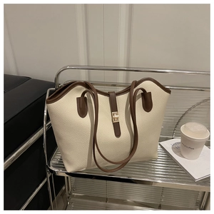 Detail view of cream white lychee leather tote with brown trim and golden buckle