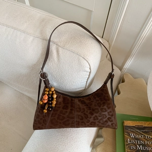 Sac hobo imprimé léopard marron avec breloque en perles de bois sur canapé blanc
