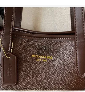 Close-up of deep brown lychee texture leather handbag with gold MIKAXIQI logo lettering