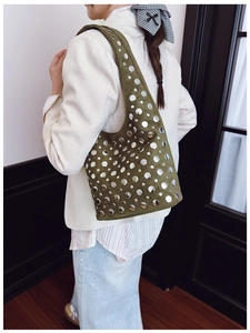 Dettaglio borsa hobo in finta pelle scamosciata verde con borchie e blazer bianco