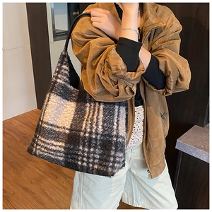 Detail of plaid faux shearling tote bag with leather strap shown in a daily lifestyle setting