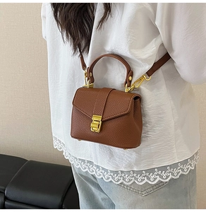 Detail of vintage caramel brown crossbody bag with lychee grain texture and gold lock
