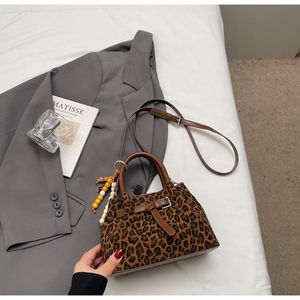 Détail du sac à main imprimé léopard avec anses en cuir marron et breloque perlée