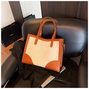 Detail of a color-block leather tote bag on a leather chair for daily commuting