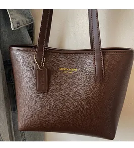 Close-up of deep brown lychee texture leather tote bag with gold logo and leather tag