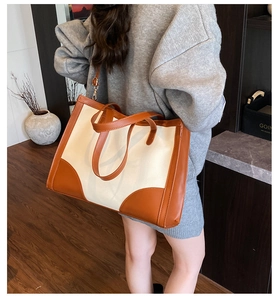 Detail view of large canvas tote bag with leather trim and shoulder strap on model