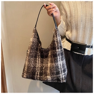 Close-up of retro plaid wool hobo bag with black leather strap on a beige sweater