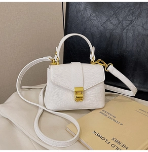 Detail of white lychee leather texture and golden metal buckle on a crossbody bag