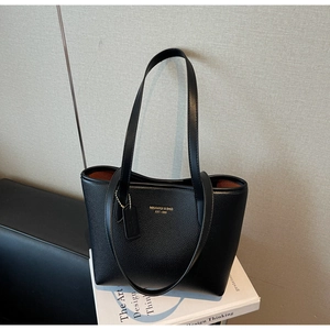 Detail of black lychee grain leather tote bag with gold logo and contrast lining