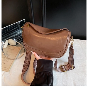 Detail of dark brown dumpling bag with wide geometric woven strap and smooth faux leather