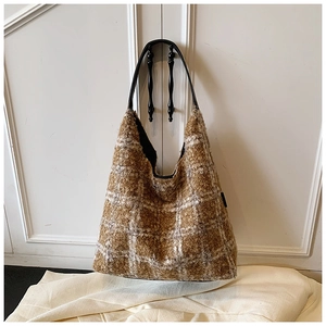 Detail of checkered plush tote bag featuring soft faux shearling and leather shoulder strap