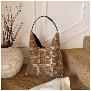 Detail of hobo bag in brown plaid wool with black leather strap on a rustic staircase