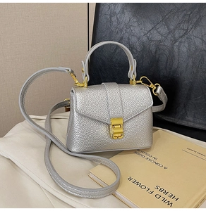 Detail of silver lychee texture handbag with gold metal lock and detachable strap