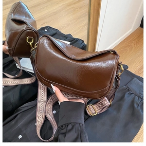 Close-up of retro brown oily leather dumpling bag with vintage wide woven shoulder strap