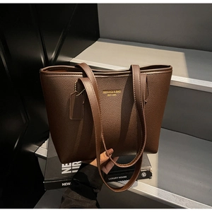 Close-up of deep brown lychee texture tote bag with golden logo and elegant handle