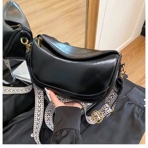 Close-up of retro black oil-waxed half-moon bag with geometric wide strap and gold hardware