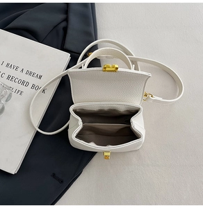 Detail view of cream lychee leather handbag showing double interior compartments and gold hardware
