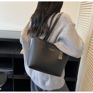 Close-up of black lychee grain tote bag featuring golden logo and leather hangtag