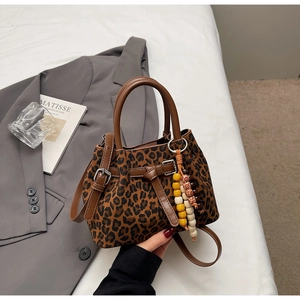 Détail d'un sac à main léopard avec poignées marron et pendentif décoratif en perles