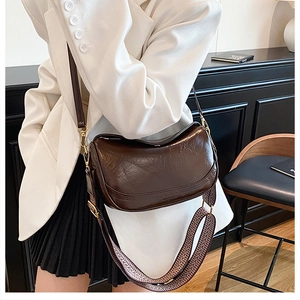 Detail of dark brown wax leather crossbody bag with vintage woven wide strap
