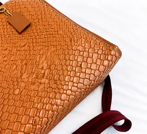 Detail der braun geflochtenen Kunstledertasche mit rot-braun gestreiftem Textilschultergurt