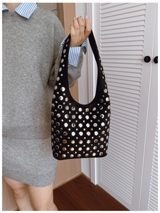 Détail d'un sac cabas noir avec rivets métalliques argentés porté par un mannequin chic