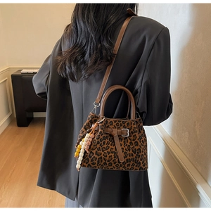 Détail du sac seau à motif léopard avec poignées en cuir et pendentif en perles