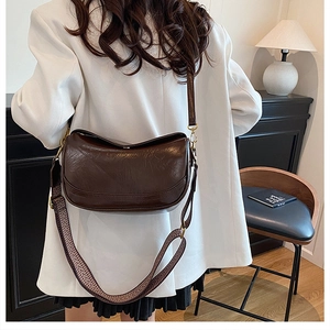 Detail of vintage brown half-moon bag featuring pleated leather and wide woven strap