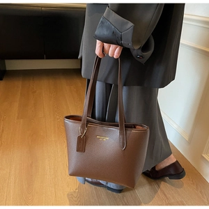 Detail of dark brown lychee texture leather tote bag with gold logo and shoulder strap