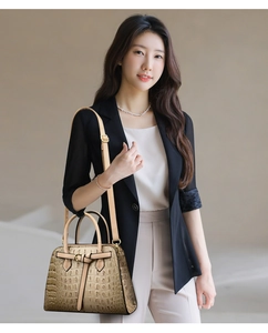 Close-up of khaki crocodile pattern handbag with elegant knotted strap and dual handles
