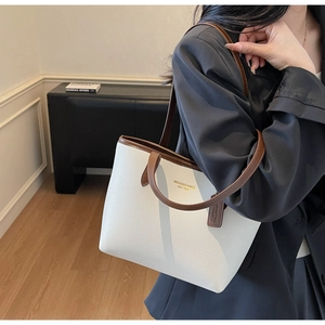 Detail of white lychee leather tote bag with dark brown straps and gold brand lettering