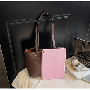 Detail of dark brown pebble leather tote bag with long handles and commute items