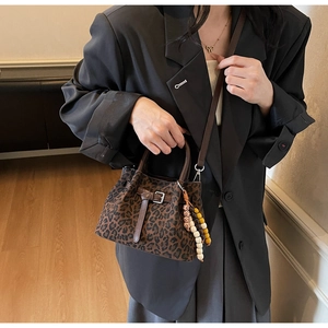 Vue détaillée du sac à main léopard avec poignées en cuir et breloque en perles colorées