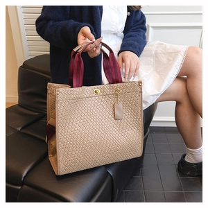 Detailaufnahme der khakifarbenen Web-Tasche mit weinroten Griffen und Metalldrehverschluss