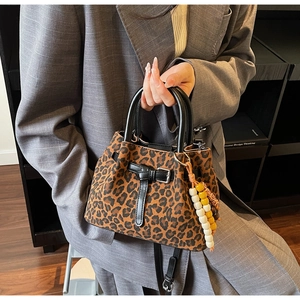 Détail du sac à main imprimé léopard avec garnitures en cuir noir et breloque perlée