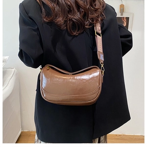 Rear view of model wearing a vintage brown crescent bag with patterned wide strap