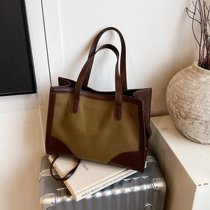 Minimalist large tote bag with olive canvas and brown leather trim on suitcase