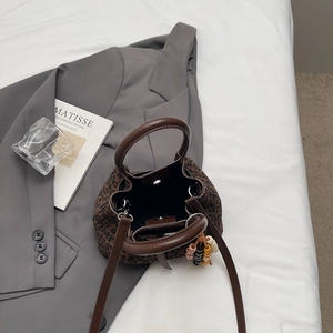 Détail du sac seau léopard avec fermoir magnétique et breloque en perles sur lin blanc