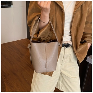 Detail of grey lychee leather bucket bag showing wide handle and side strap clasp