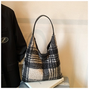 Chic black and white checkered faux shearling shoulder bag with leather strap on luggage