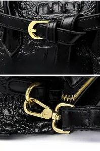 Detail of glossy black crocodile embossed texture with pale gold hardware and swivel hook