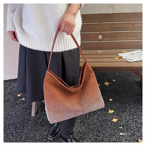 Detail of a brown suede bag featuring sparkling gradient rhinestones and leather handles