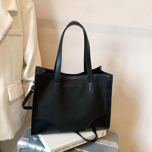 Minimalist large capacity black tote bag with canvas and leather patchwork on studio background